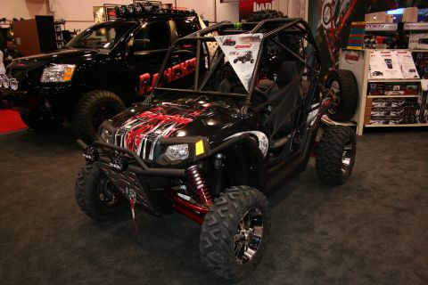 1998 Ford Crown Victoria - A black off-road buggy with striking red and white graphics is displayed indoors, with a black pickup truck visible behind it.