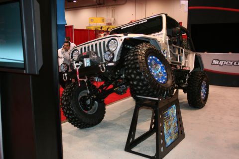 1998 Ford Crown Victoria - A heavily modified Jeep Wrangler is displayed on a stand at an auto show.