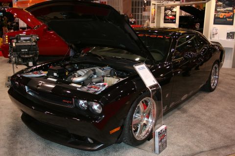 1998 Ford Crown Victoria - A black Dodge Challenger SRT8 is displayed with its hood open, revealing the engine and SRT badging.