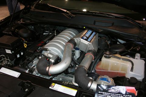 1998 Ford Crown Victoria - The engine bay of a car shows a prominent supercharger and associated plumbing.
