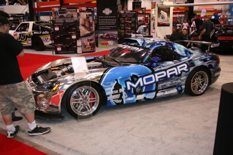 1998 Ford Crown Victoria - A highly customized Dodge Viper, wrapped in Mopar livery, is displayed with its hood open at an indoor event.