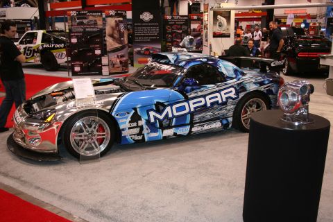 1998 Ford Crown Victoria - A highly customized sports car with Mopar livery is displayed indoors, with its hood open.