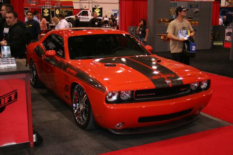 1998 Ford Crown Victoria - Customized orange Dodge Challenger with black stripes and chrome wheels at an auto show.