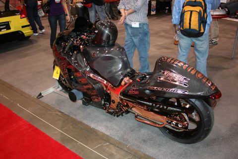1998 Ford Crown Victoria - A heavily modified motorcycle with a dark finish and copper detailing is displayed indoors.