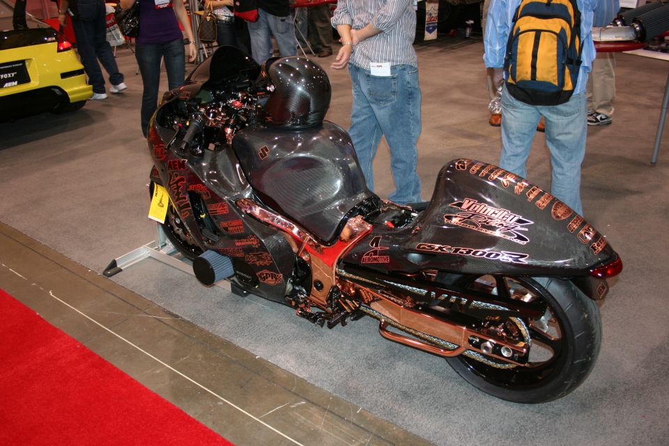 Customized black motorcycle with copper accents and numerous stickers, viewed from the side