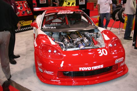1998 Ford Crown Victoria - Race car with exposed engine and sponsor decals on display at an event.