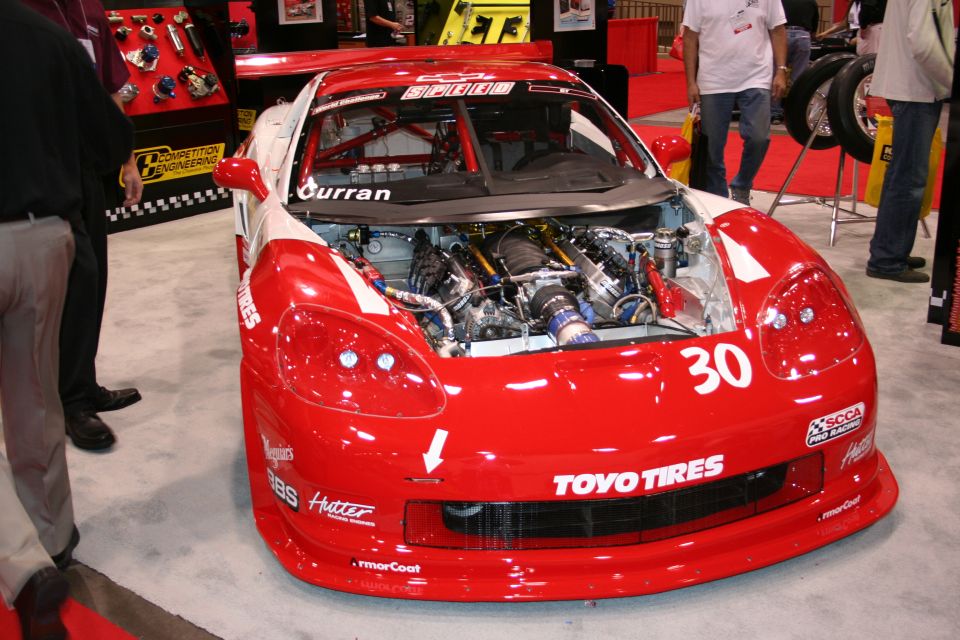 Red and white race car with number 30 on the front, engine exposed. Various sponsor decals visible