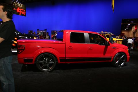 1998 Ford Crown Victoria - Red Ford F-150 pickup truck with black racing stripes and custom wheels on display.