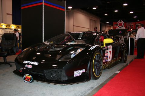 1998 Ford Crown Victoria - A black sports car, likely a Lamborghini, is displayed indoors with various racing sponsorships visible on its body.