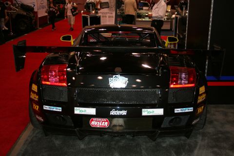 1998 Ford Crown Victoria - Rear view of a black Lamborghini Gallardo race car with a prominent rear wing and various sponsor decals.