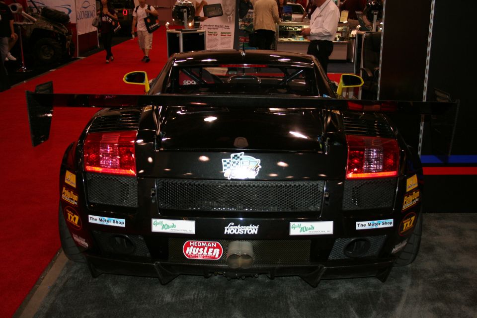 Black Lamborghini Gallardo rear with large wing and racing stickers. "Lamborghini Houston" sticker visible