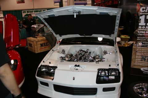 1998 Ford Crown Victoria - A white sports car is displayed with its hood open, revealing a highly polished chrome engine and components.