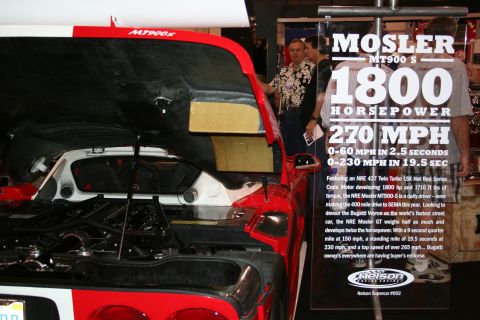 1998 Ford Crown Victoria - A Mosler MT900 S is displayed with its engine exposed, next to a sign detailing its performance.