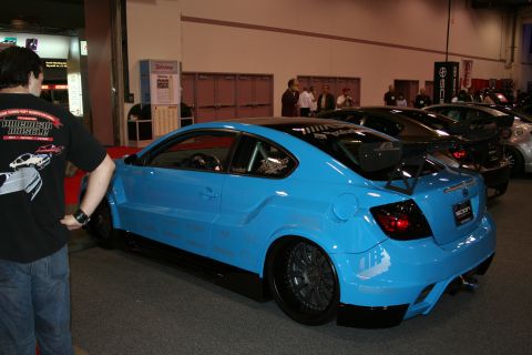 1998 Ford Crown Victoria - A modified blue Scion tC is displayed at an indoor event, with other vehicles visible in the background.