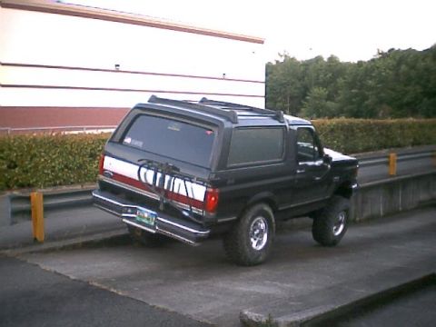 1988 Ford Bronco - This black Ford Bronco is seen from a rear-left angle, equipped with a bike rack on its tailgate.