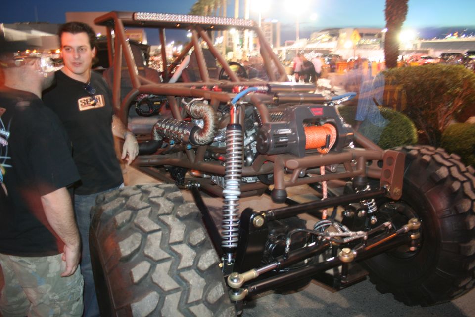 Custom off-road buggy with large tires, exposed engine, and a winch mounted on the front
