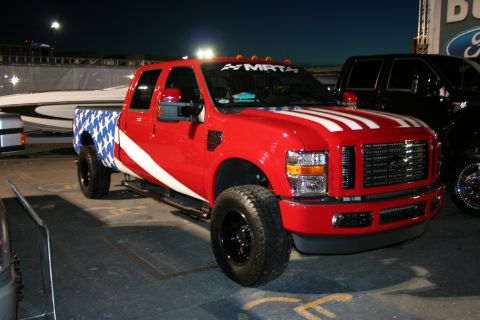 1998 Ford Crown Victoria - A red pickup truck with patriotic graphics is parked next to another vehicle under artificial lighting.