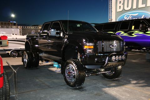 1998 Ford Crown Victoria - A black lifted dually pickup truck is displayed with custom chrome accents and large off-road tires.