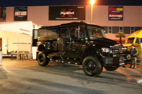 1998 Ford Crown Victoria - A custom black truck with large tires and a bull bar is parked at an outdoor event.