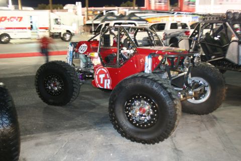 1998 Ford Crown Victoria - A custom-built red off-road buggy with a roll cage and large tires is parked next to other vehicles.