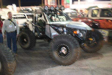 1998 Ford Crown Victoria - This custom off-road buggy features oversized tires and a prominent roll cage, seen alongside other vehicles.