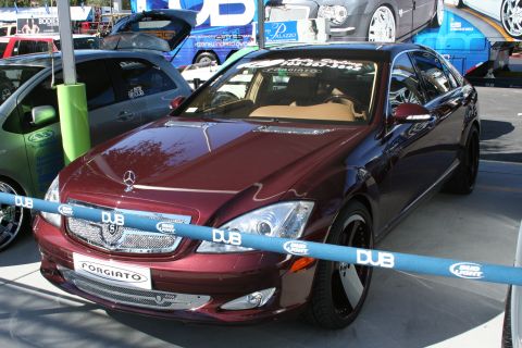 1998 Ford Crown Victoria - A maroon Mercedes-Benz S-Class is parked outdoors, with other vehicles and banners visible in the background.