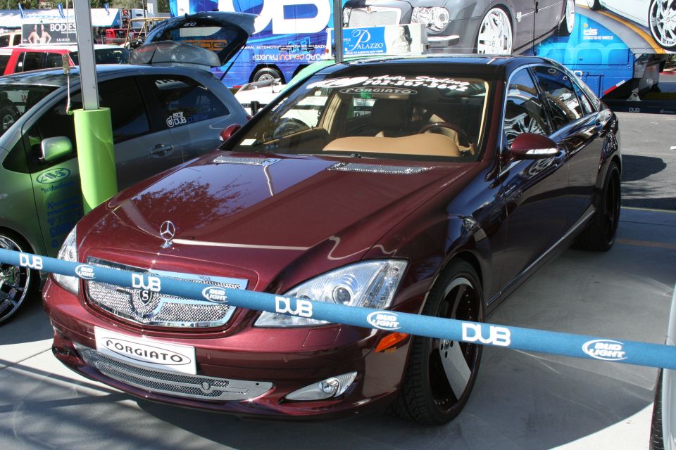 Maroon Mercedes S-Class with Forgiato wheels and DUB branding on a blue barrier
