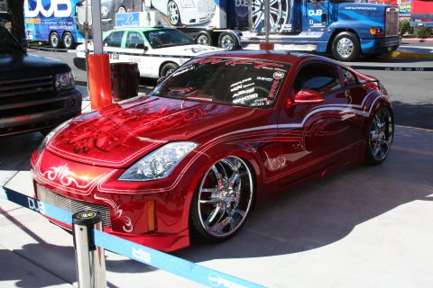 1998 Ford Crown Victoria - A custom red sports car with elaborate pinstriping and large chrome wheels is displayed outdoors.
