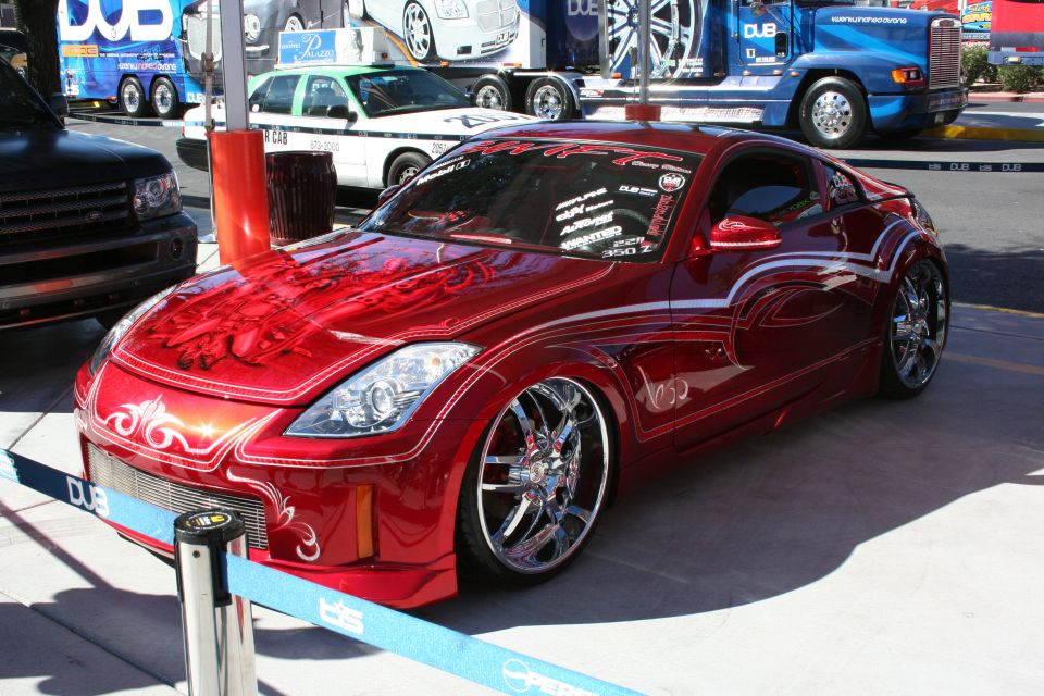 Red custom sports car with white pinstriping and chrome wheels, front 3/4 view