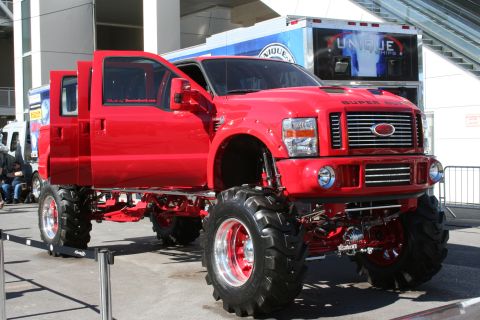 1998 Ford Crown Victoria - This heavily modified red Ford Super Duty truck features an extreme lift kit and oversized tires, making a bold statement.
