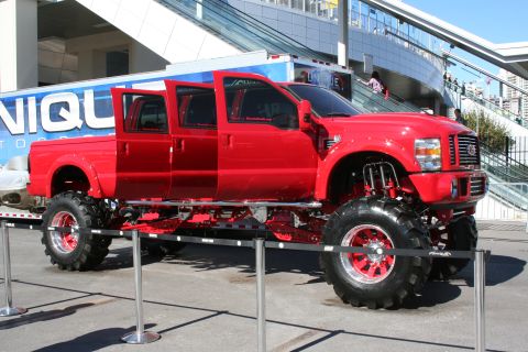 1998 Ford Crown Victoria - Customized red Ford Super Duty pickup truck on display with massive tires and lifted suspension.