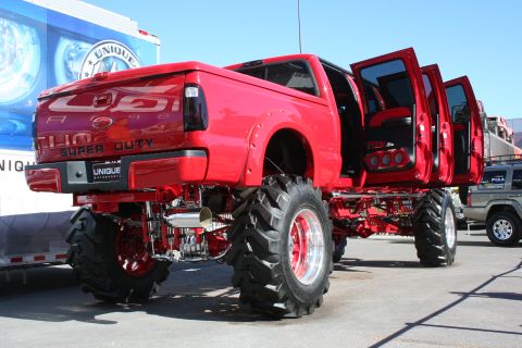 1998 Ford Crown Victoria - This heavily modified red Ford Super Duty truck features an extreme lift kit and custom doors.