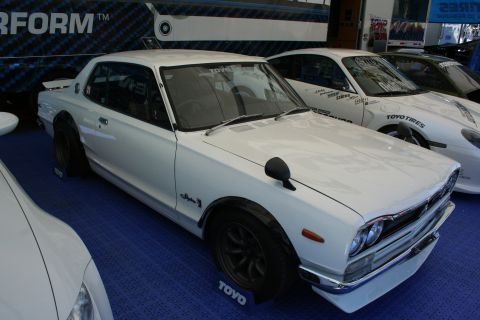 1998 Ford Crown Victoria - A white classic coupe with fender flares is displayed next to other vehicles.