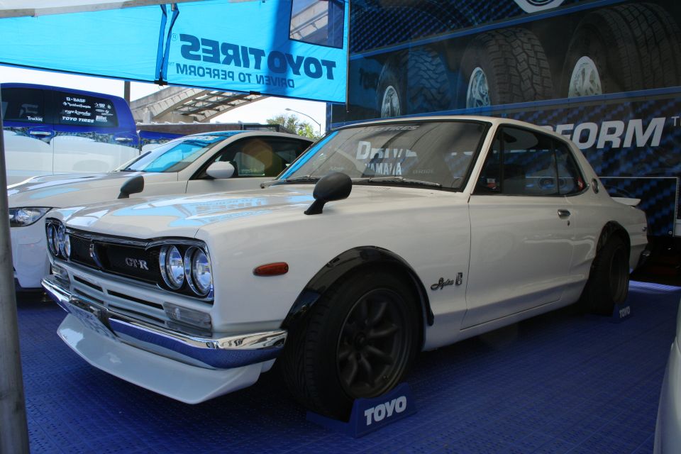 White 1973 Nissan Skyline GT-R with fender flares and aftermarket wheels, parked next to another car