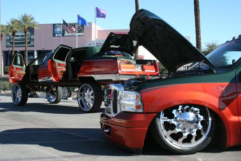 1998 Ford Crown Victoria - Two heavily customized vehicles, a truck and a car, are parked outside on a sunny day.
