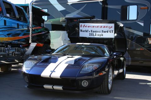 1998 Ford Crown Victoria - A blue Ford GT with white racing stripes is displayed in front of a large RV and a custom truck.