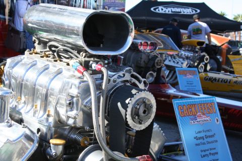 1998 Ford Crown Victoria - Supercharged engine on display at a drag racing event, with dragsters visible behind it.
