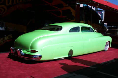 1998 Ford Crown Victoria - A custom coupe with a distinctive rounded rear end and chrome accents is displayed on a red carpet.