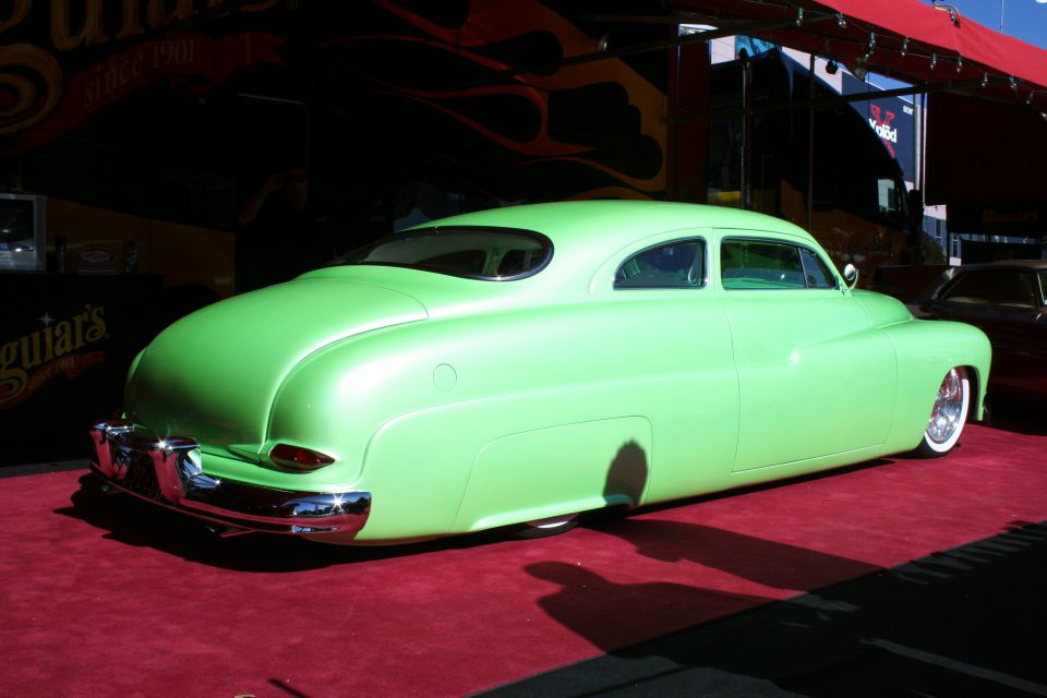 Lime green custom coupe with chrome bumper and whitewall tires, parked on a red carpet