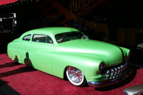 1998 Ford Crown Victoria - A lime green custom coupe with a distinctive grille and lowered stance sits on a red carpet.