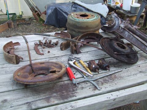 1967 Ford Bronco - Collection of vintage brake components and mechanic's tools scattered on a wooden table outdoors.