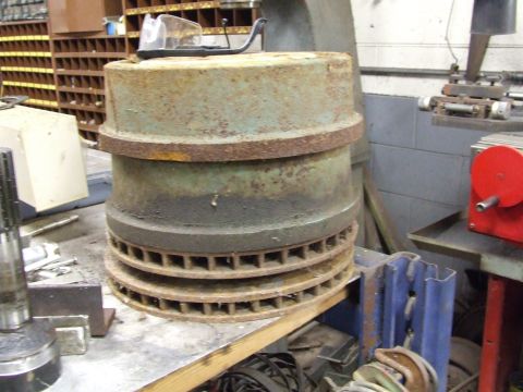 1967 Ford Bronco - Rusty brake components are piled on a workbench in a workshop setting.