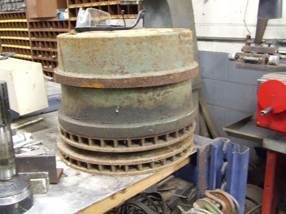 Stack of rusty brake drums and rotors on a workbench