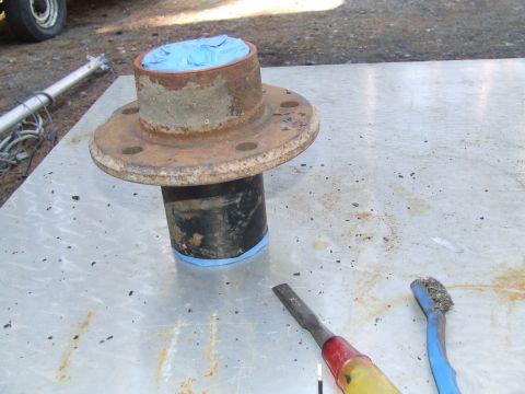 1967 Ford Bronco - Wheel hub with blue tape, resting on a metal surface with tools. The year is not visible.