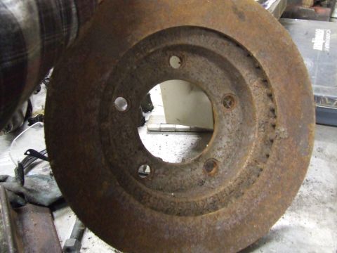 1967 Ford Bronco - A heavily rusted brake rotor is held up for inspection, showing signs of wear and damage.