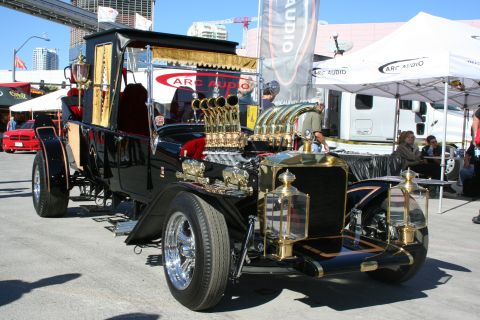 1998 Ford Crown Victoria - A heavily customized hot rod with a prominent V8 engine and gold trim is displayed outdoors, with other vehicles and tents in the backgroun…