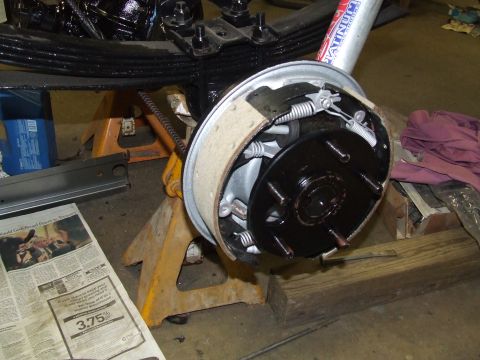 1967 Ford Bronco - Close-up of a vehicle's rear drum brake assembly, supported by jack stands.