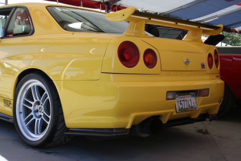 1998 Ford Crown Victoria - Rear view of a yellow Nissan Skyline GT-R, a prominent spoiler and aftermarket wheels.