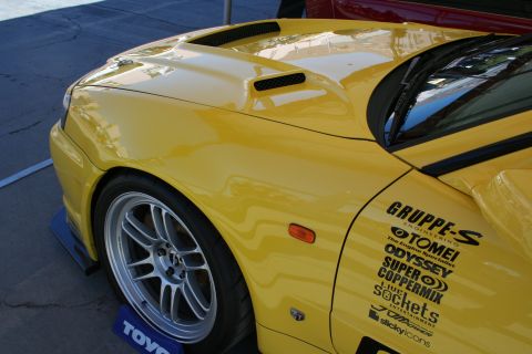 1998 Ford Crown Victoria - Close-up of a yellow sports car's fender and hood, showing racing decals on the door.