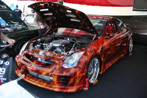 1998 Ford Crown Victoria - A customized coupe with a flame paint job is displayed with its hood open, revealing the engine and interior.